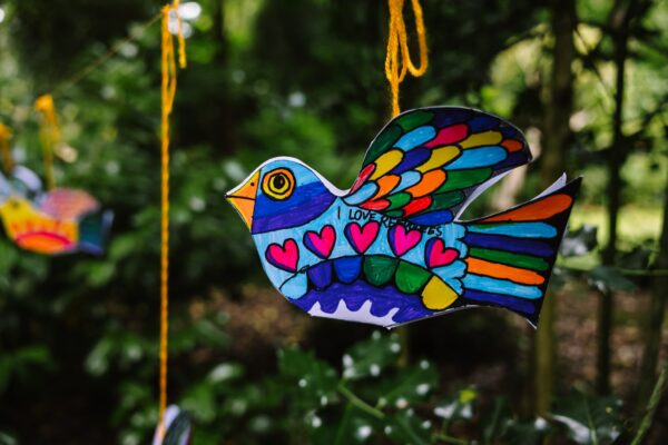 Colourful handmade paper bird hanging from a branch